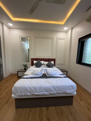 A modern bedroom with a large bed, bedside tables, a mirror, and a window with blinds. - Hotel Chaufula Garden Restaurant Lodging (Pimpale Jagatap)