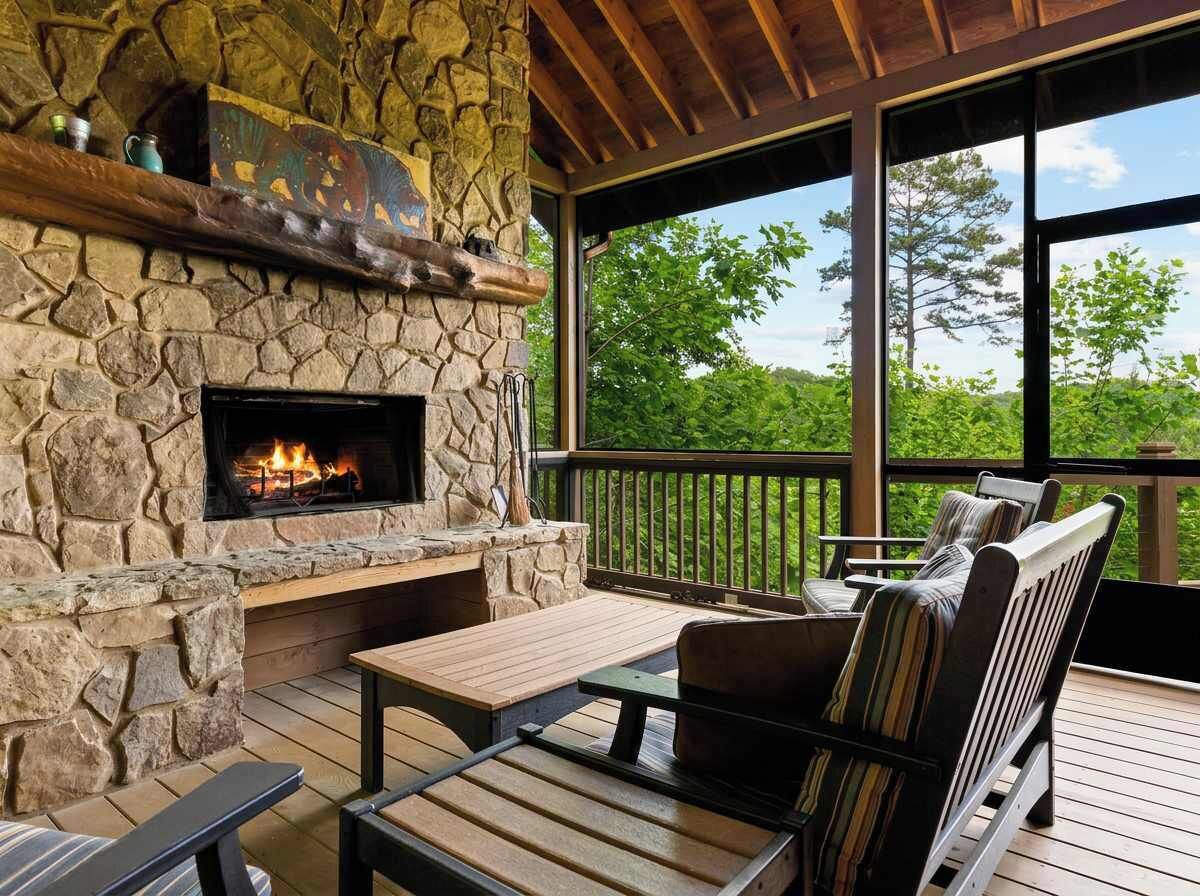 A stone fireplace with a fire, wooden deck seating, and a view of trees.