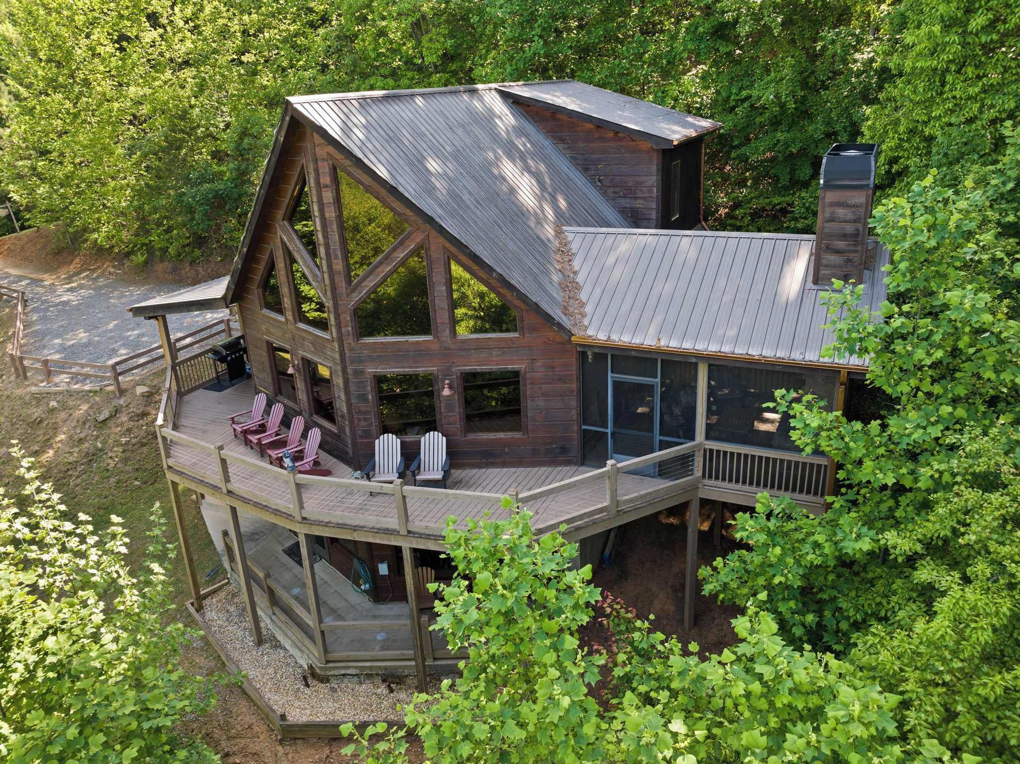 Une cabane dotée d’une grande terrasse, de nombreuses fenêtres et d’une cheminée.