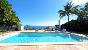 Une piscine avec des chaises longues et vue sur l’océan.