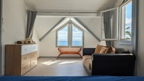 Une chambre avec un lit, une commode, un canapé et une fenêtre donnant sur la mer.