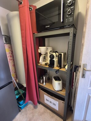 Una kitchenette con microondas, cafetera, tostadora y un armario con la etiqueta 'BAC DE TRI'.