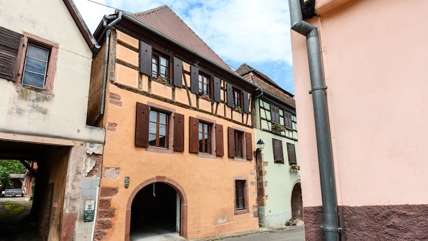 Een klassiek Europees gebouw met een begane grond ingang, bovenlichten met luiken en een zichtbare lantaarnpaal.