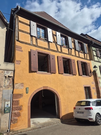 A building with a yellow facade, multiple windows with shutters, and an archway entrance.. Holiday Home 'Voyage En Alsace Chez Gaby' with Wi-Fi