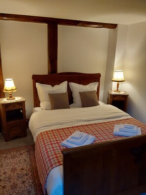 A neatly made bed with a checkered bedspread, two bedside lamps, and a wooden headboard.