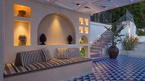 A modern outdoor seating area with a sofa, decorative vases, and a staircase with patterned steps. - Luxury Villa with Private Pool, Capri Views and Panoramic Rooftop (Campania)