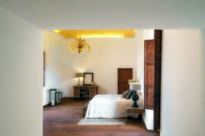 Ein Schlafzimmer mit einem Bett, Nachttischlampen, einem Schminktisch, einem Spiegel, einer Kronleuchter und einer Holztür.