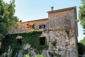 Un edificio de piedra con techo de tejas, balcón y hiedra.
