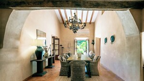 Un espace repas en forme d’arche, avec des chaises en osier, une table en bois et un lustre.