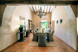 An arched dining area with wicker chairs, a wooden table, and a chandelier.