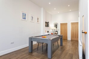 A pool table with balls, a lamp, and a mirror in a room with wooden flooring and white walls. - Chic 2-Bed Seaside Escape in Vibrant Kemp Town (Brighton and Hove)