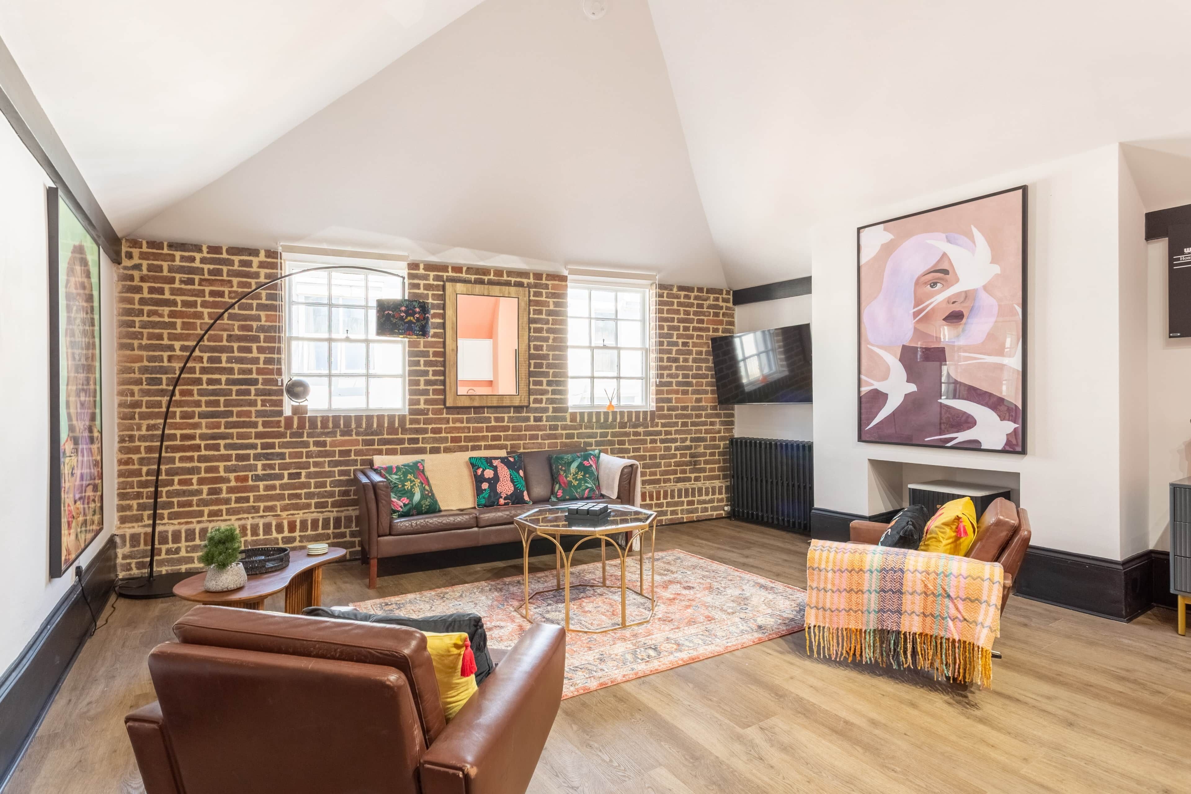 Un salón tipo loft con pared de ladrillo, un sofá, una mesa de centro y un televisor montado en la pared.
