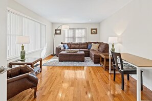 Een woonkamer met een bruine leren bank, een houten eettafel en een stoel.