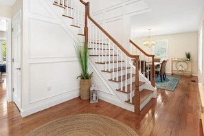 Eine Treppe mit Holzstufen und weißen Geländern, ein Essbereich mit Tisch und Stühlen sowie ein Blumentopf.