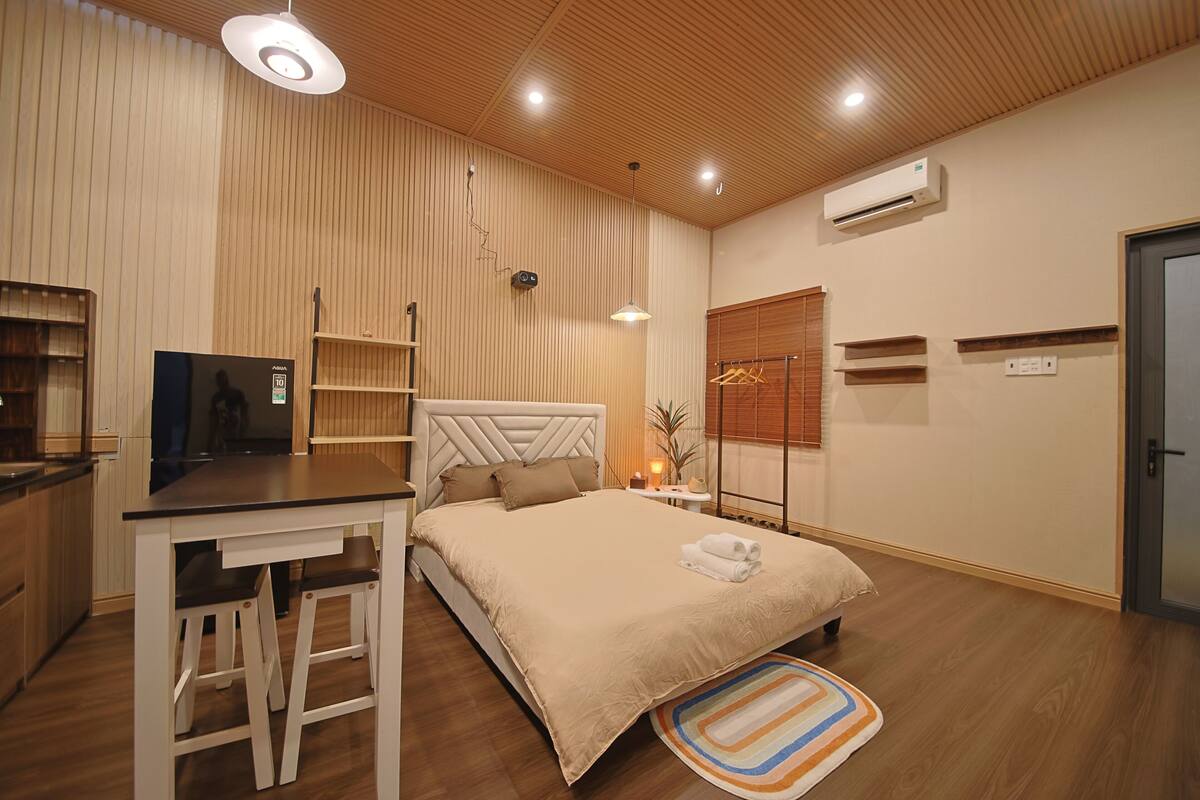Een slaapkamer met een bed, nachtkastjes, een bureau en een televisie.