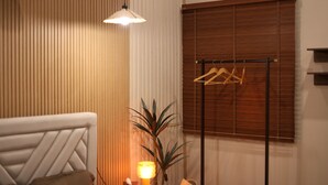 Una habitación de hotel ordenada con cama, mesita de noche, lámpara y un panel de pared de madera.