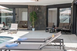 Een moderne buitenlounge met een zwembad, zitplaatsen en een potplant.