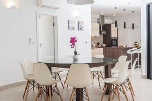 Een moderne eethoek met een glazen tafel, witte stoelen en een potorkidee.