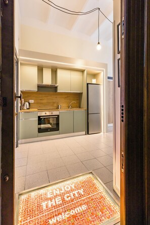 A modern kitchen with a built-in oven, a refrigerator, and a wooden countertop. - Urban Retreat 76 (Naples)