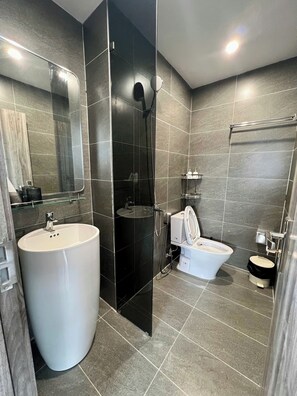 Et moderne badeværelse med en stor, hvid vask, toilet og bruseniche.