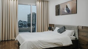 A hotel room with a large bed, a view of the city, and a painting on the wall. - Studio Suite Deluxe 35m2 with Balcony (Hà Nội)