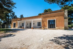 A building with a gravel driveway, white columns, and large windows.