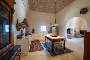 A spacious kitchen with white cabinets, a dining table, and a large window.