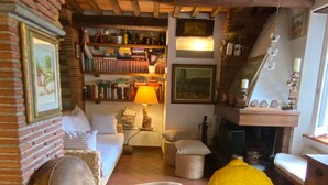Een gezellige woonkamer met een open haard, een boekenkast en een tafel met een glazen pot vol citroenen.