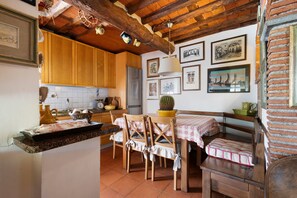 A rustic kitchen with wooden cabinets, a tiled backsplash, and a dining area with a bench and chairs. - La Corte Dei Limoni - Countryside Retreat with Mountain View, Wi-Fi & Air Conditioning (Nocchi)