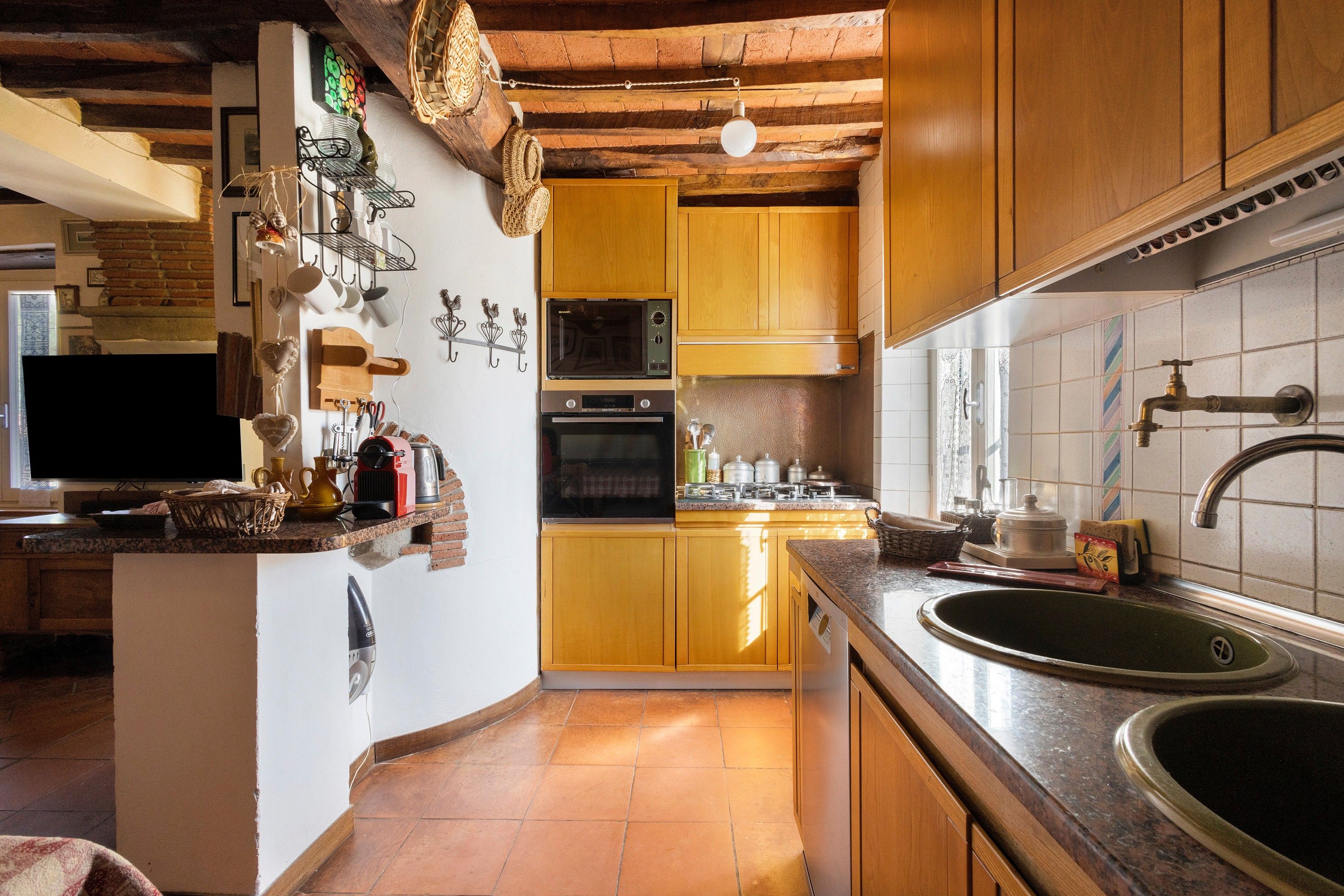 A kitchen with wooden cabinets, a microwave, an oven, and a sink.