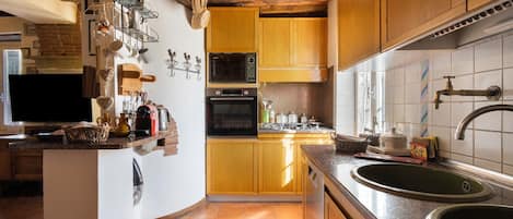 A kitchen with wooden cabinets, a microwave, an oven, and a sink.