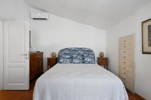 Quarto com cama, guarda-roupa, penteadeira, ar condicionado e quadro pendurado na parede.