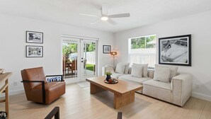 A living room with a brown leather chair, a beige sofa, a wooden coffee table, and a ceiling fan. - The Full Florida Experience -Pool, Bikes and Beach (Naples)