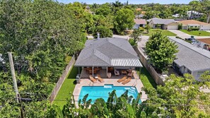Ein Wohnhaus mit Pool, Terrassenmöbeln und einem umzäunten Garten.