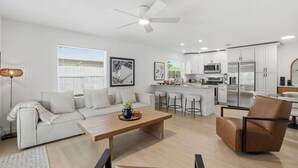 A modern living room with a sofa, coffee table, and a dining area. - The Full Florida Experience -Pool, Bikes and Beach (Naples)