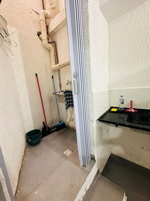 A small bathroom with a black sink, a green bucket, a red broom, and a blue mop. - Vrbo Property (São Paulo)