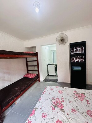 A room with bunk beds, a fan, a wardrobe, and a door leading to another room. - Vrbo Property (São Paulo)