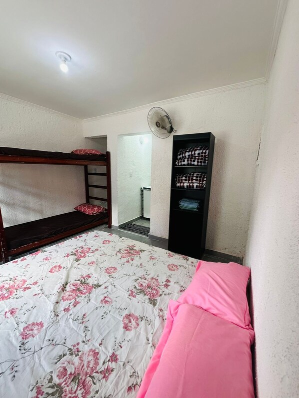 A room with a bunk bed, a standing fan, a wardrobe, and a door leading to another room. - Vrbo Property (São Paulo)