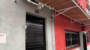Un edificio con una puerta de obturador negro cerrada, el número '10' sobre ella, y una fachada roja y gris.
