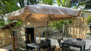 An outdoor patio with a brick wall, a covered table, and chairs. - Villa BRUNI Wine Guest House (Montefalco)