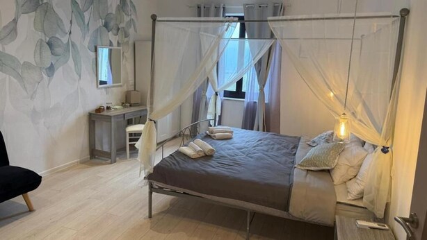 A bedroom with a four-poster bed, a desk, a chair, and a bedside table. - Villa BRUNI Wine Guest House (Montefalco)