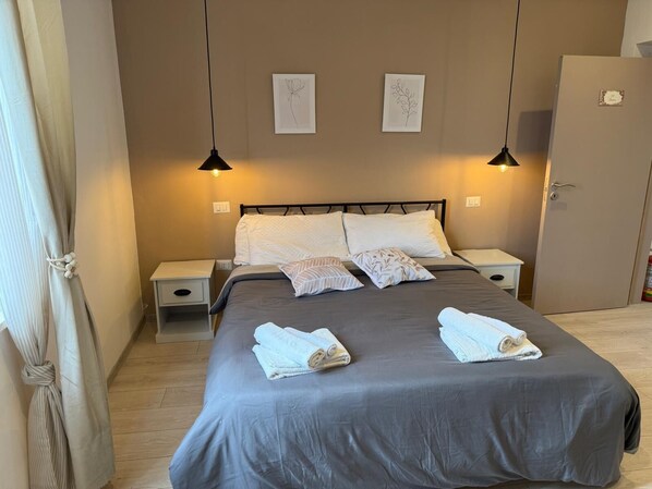 Un dormitorio con una cama, dos mesitas de noche, un armario y dos lámparas de pared.