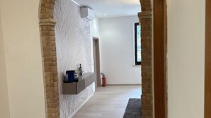 A hallway with a brick archway, a fire extinguisher, a shelf with items, and a window with a view. - Villa BRUNI Wine Guest House (Montefalco)