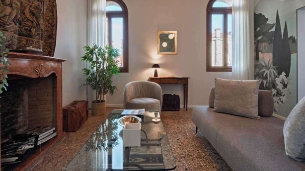 Una sala de estar con chimenea, un sofá, una mesita de centro, una lámpara y un cuadro en la pared.