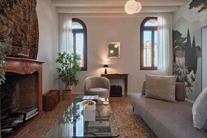 A living room with a fireplace, a sofa, a coffee table, a lamp, and a painting on the wall. - Historic Venetian Palazzo Apartment with Elevator in the Heart of San Marco (Venezia)