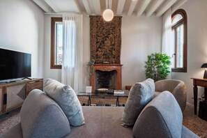 Ein Wohnzimmer mit Kamin, Fernseher und zwei grauen Sofas.