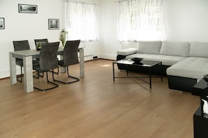 Ein modernes Wohnzimmer mit Esstisch, Stühlen, einer Couch und einem Couchtisch.