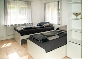 Ein Schlafzimmer mit zwei Betten, einem Heizkörper und einem weißen Regal.