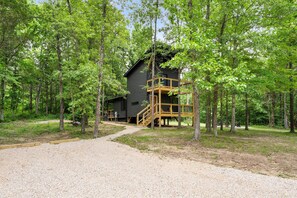 A cabin surrounded by trees with a gravel path leading to it.