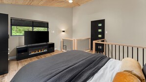 Quarto com cama, televisão, lareira, varanda e ventoinha no teto.